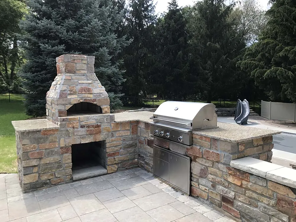 Stone outdoor kitchen with a pizza oven and built-in grill