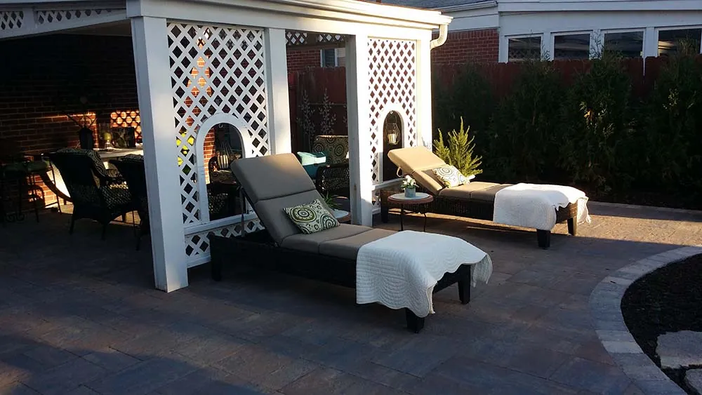 Paver patio with lounge chairs under a white pergola